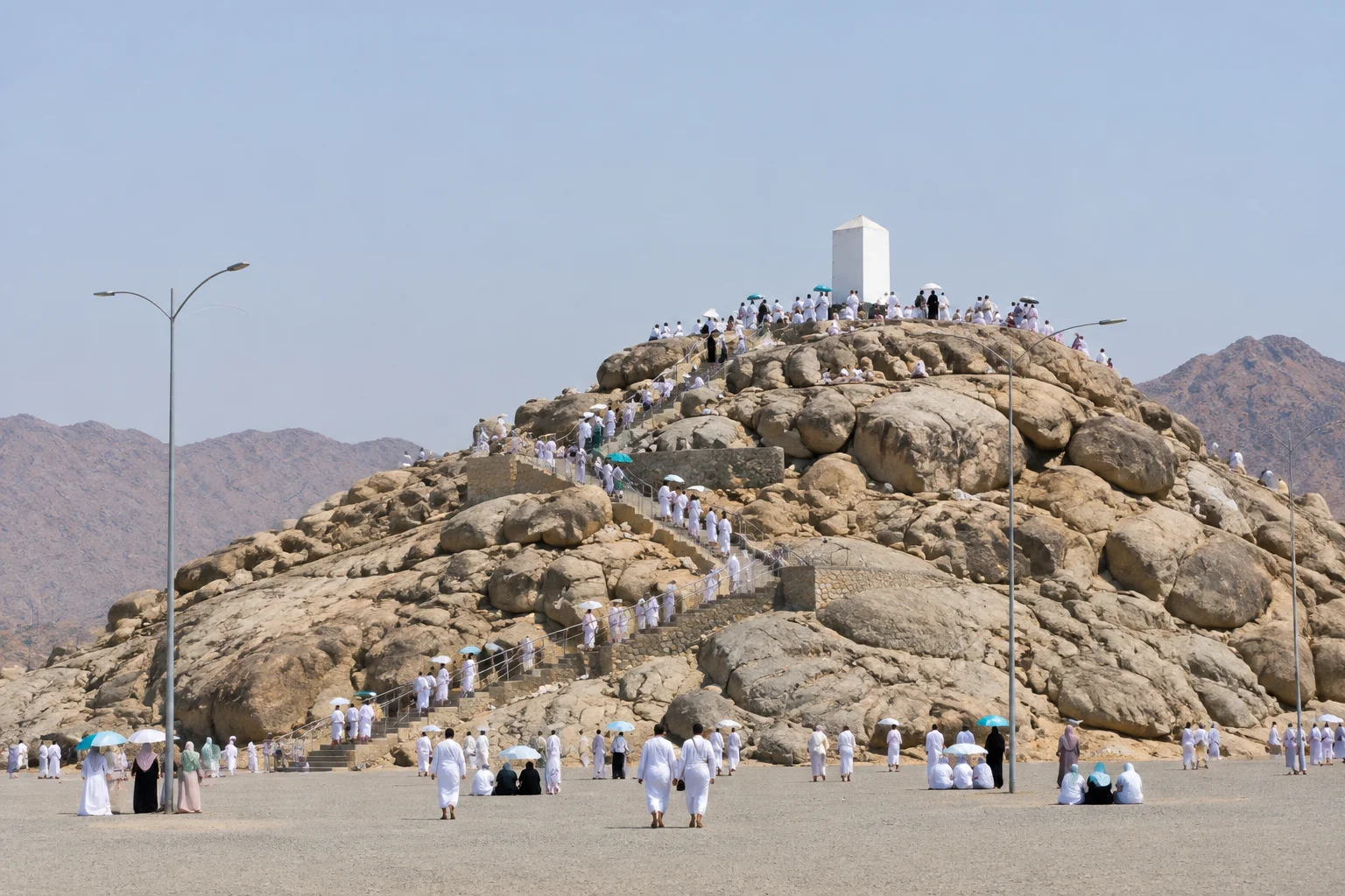 Jabal al-Rahmah, a low hill of granite boulders with a white pillar on its summit, pilgrims on its steps